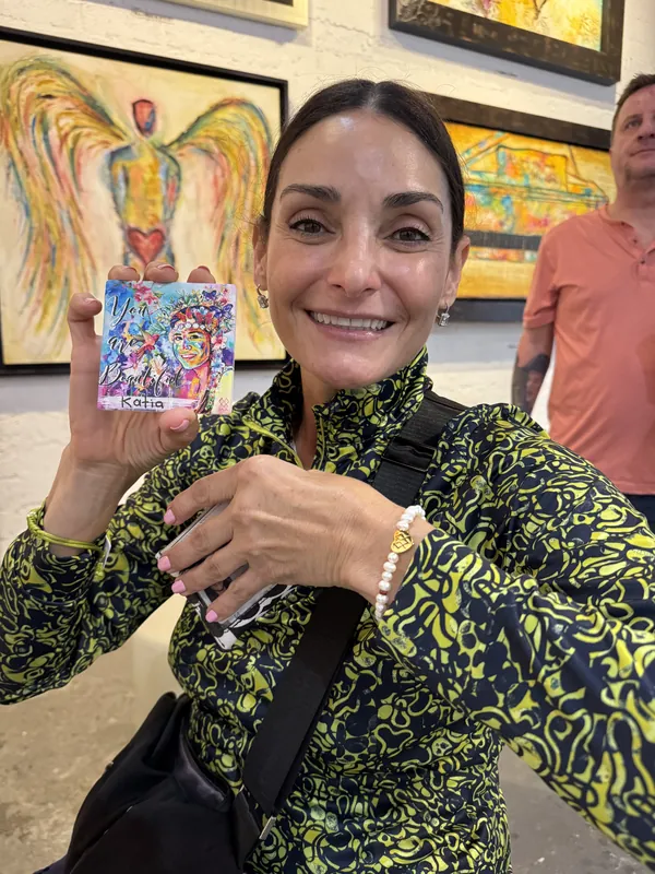Clienta radiante en la galería mostrando su cerámica MIA pintada a mano y personalizada con su nombre, Katia